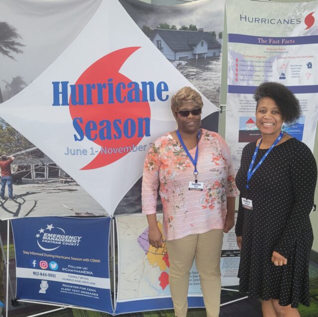 Photo of Naomi and another African American lady standing in front of a banner that says Hurricane Season