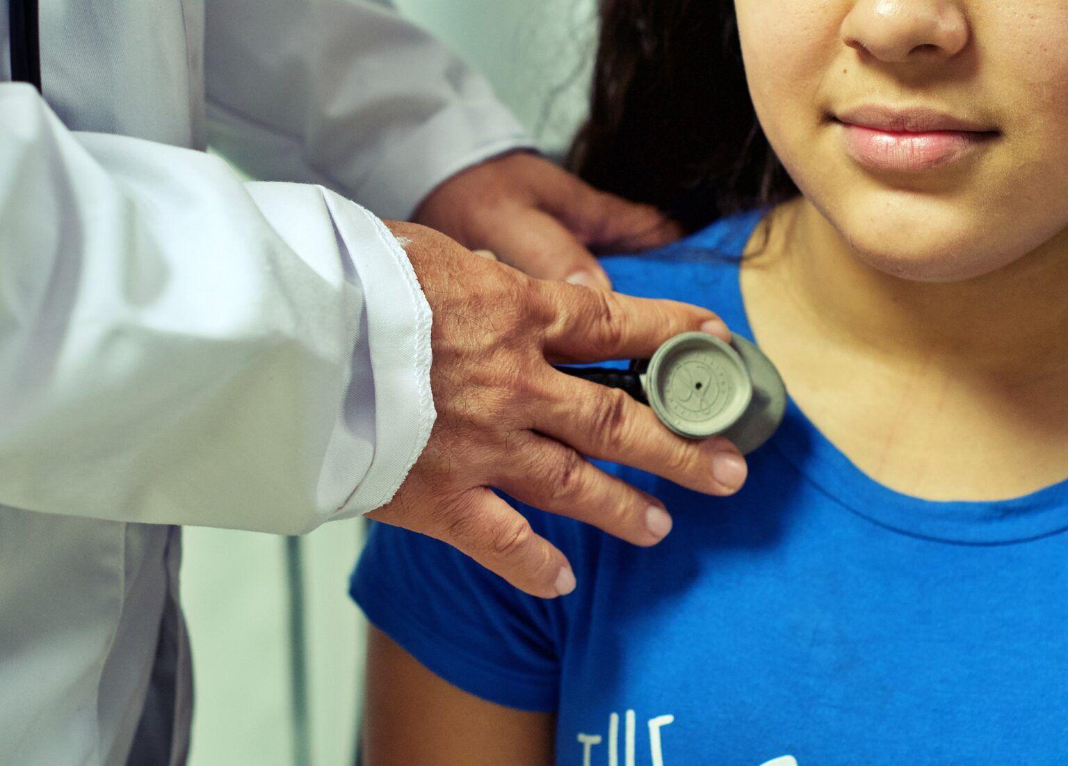 Photo of doctor with stethoscope on chest of young girl