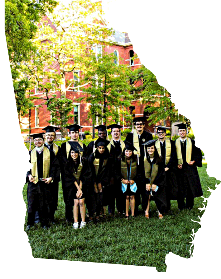 A group of IPSE students wearing their graduation caps and gowns outside of a campus building.