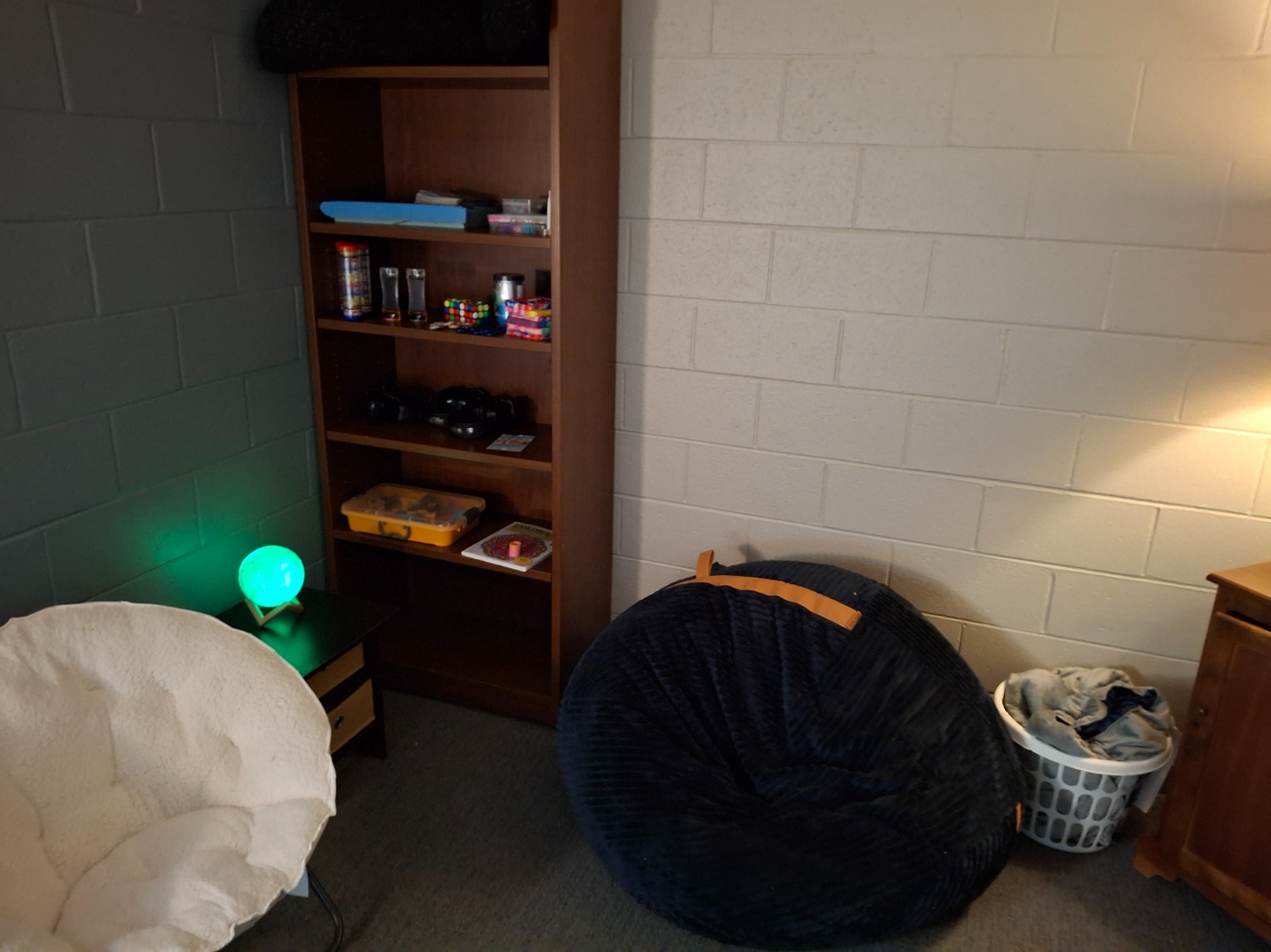 Dimly lit sensory room with beanbag and book shelf