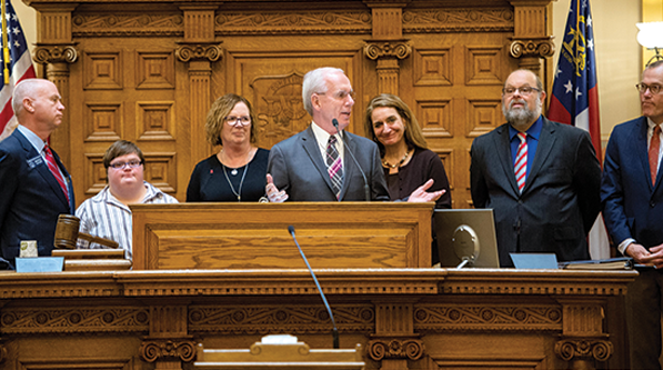 Rep. Tony Coelho (D - California) speaking about employment for people with disabilities in the Georgia Senate with (l to r) Hannah Hibben, Debbie Hibben, Elizabeth Appley and Eric Jacobson. 